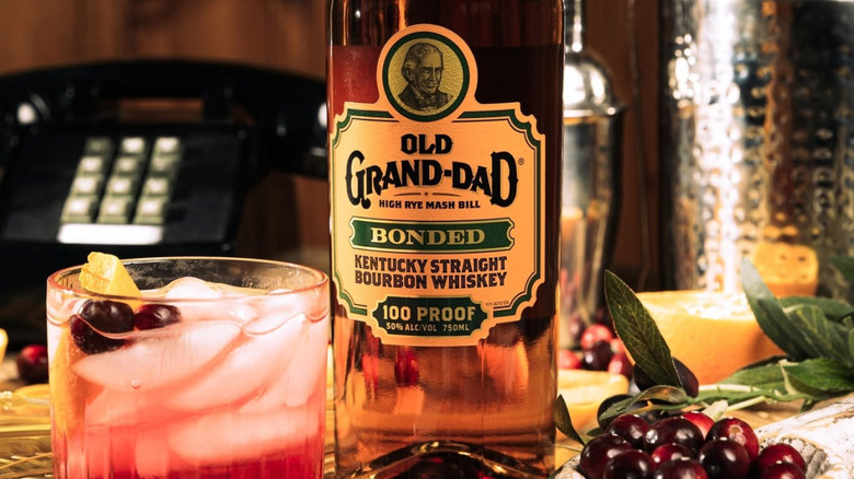 A close shot of a bottle of Old Grand-Dad Bonded surrounded by a cocktail, accessories and ingredients