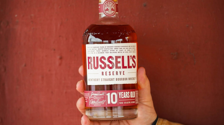 A person holding up a bottle of Russell's Reserve 10-year up to the camera
