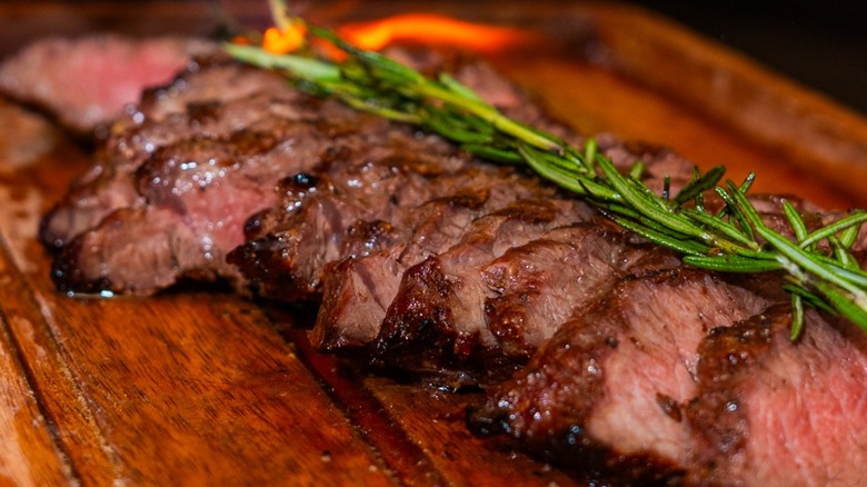 Sliced steak with rosemary on a wooden board