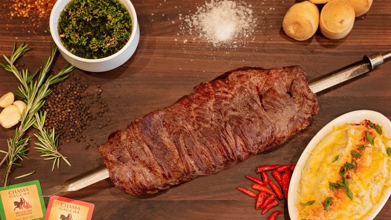 Fraldinha on a skewer on a table with spices and sides