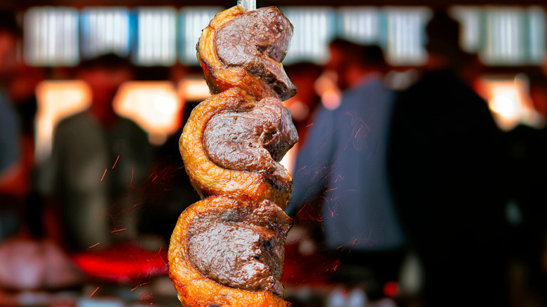 Picanha on a skewer with a blurred restaurant background
