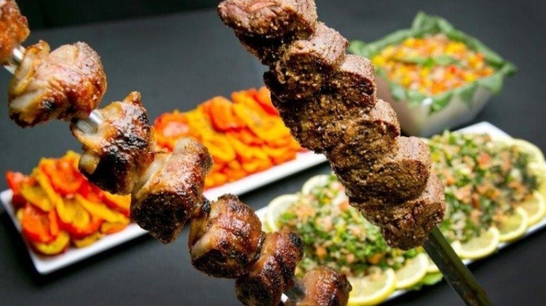 Two skewers of picanha in front of blurred sides on a table