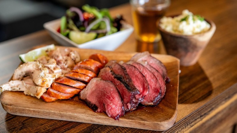 Sliced meats on a sampler platter with sides blurred in the background