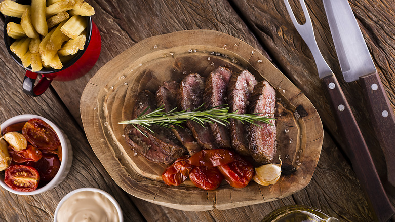 Sliced steak on a wooden board with sides