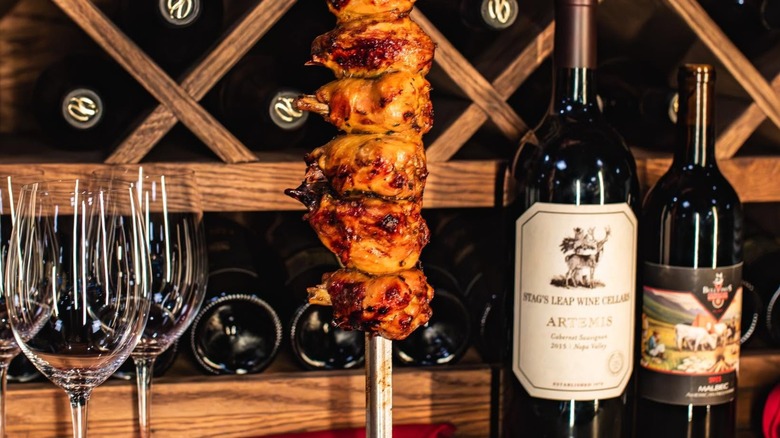 Skewer of meat with bottles of wine and wine glasses