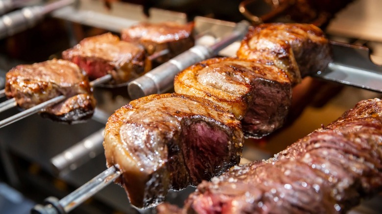 Row of meat skewers cooking