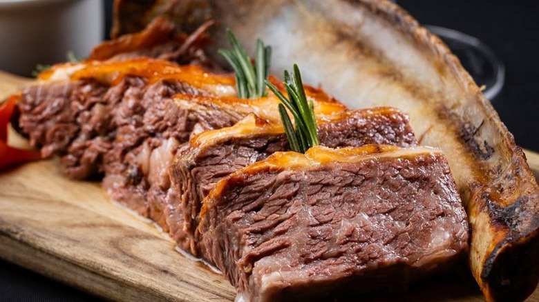 Slices of steak with rosemary on a wooden board