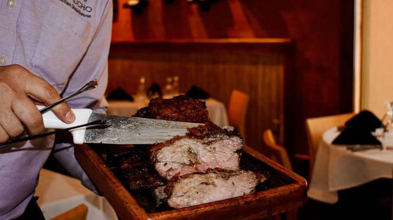 Server holding a tray and carving meats
