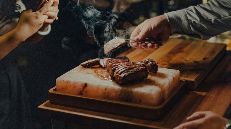 Steak being sliced and served from a salt block