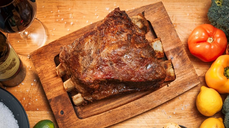 Beef ribs on a wooden board with vegetables and wine