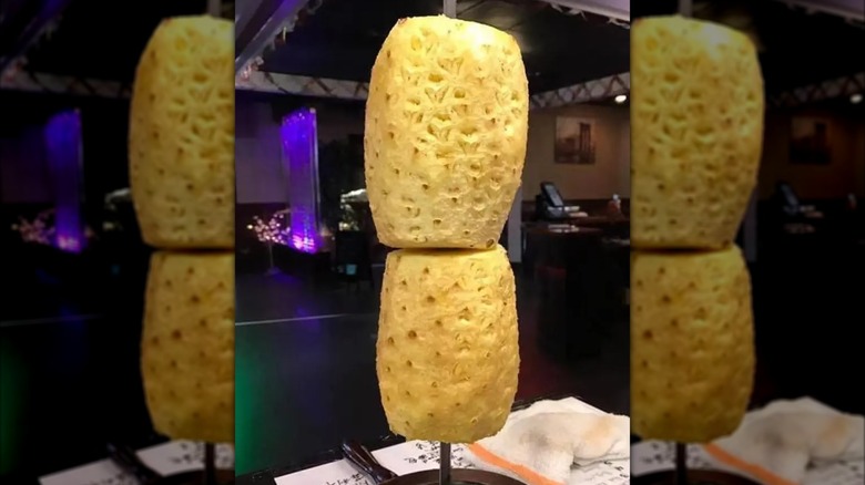 Two pineapples on a skewer on a table