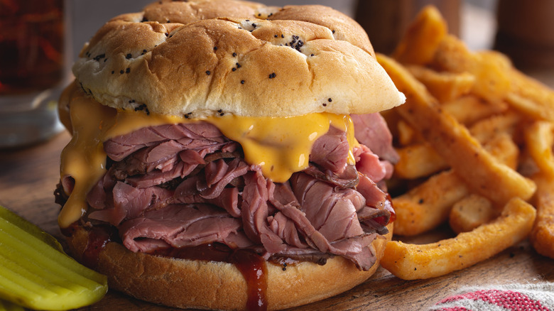a picture of Beef 'n' Cheddar with fries and a pickle on the side