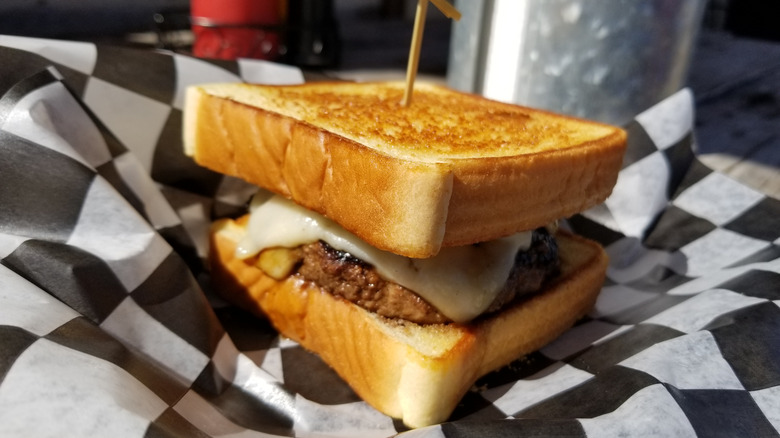 Ground beef on golden Texas toast with melted cheese on a piece of deli paper