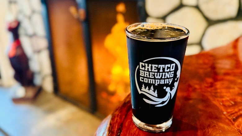 Pint of Chetco Brewing Co with fireplace blurred in background