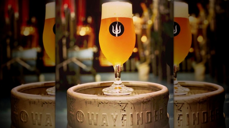 Glass of beer sitting on a Wayfinder branded keg