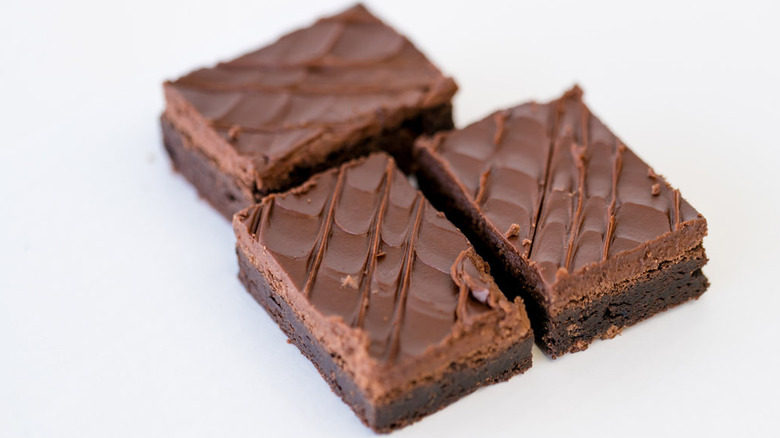 Three brownies topped with generous layers of frosting