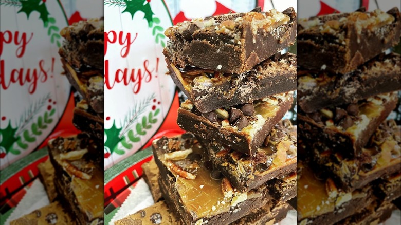 Stack of brownies with toppings like nuts in front of holiday sign