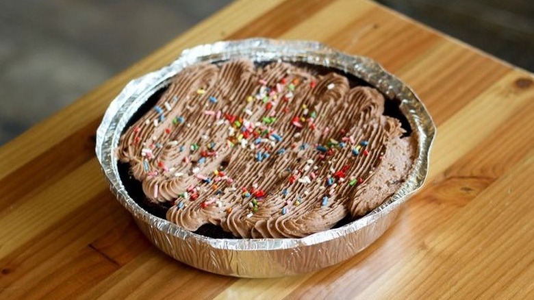 Circular pan containing brownie topped with icing and sprinkles
