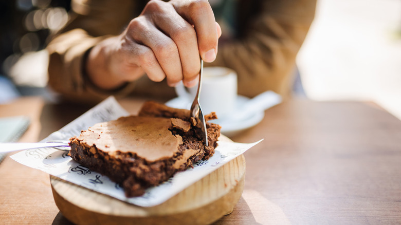 Hand taking bite out of brownie with spoon at a cafe