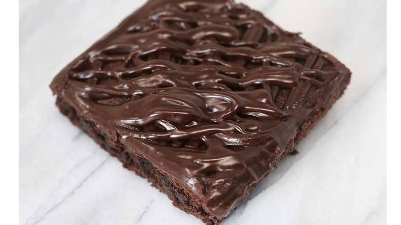 Square shaped brownie covered in drizzles of icing
