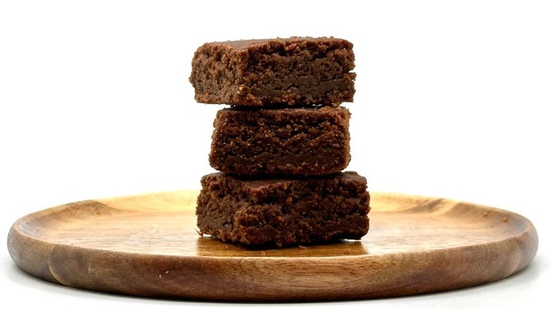 Three caramel brownies stacked on wooden platter