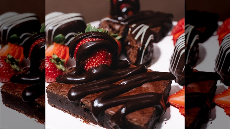 Several brownies drizzled in chocolate and topped with strawberries