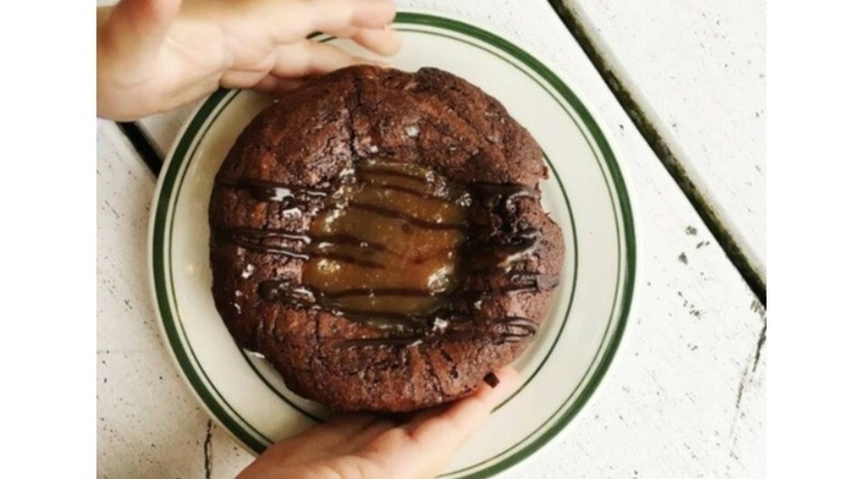 Two hands framing circular brownie drizzled with chocolate