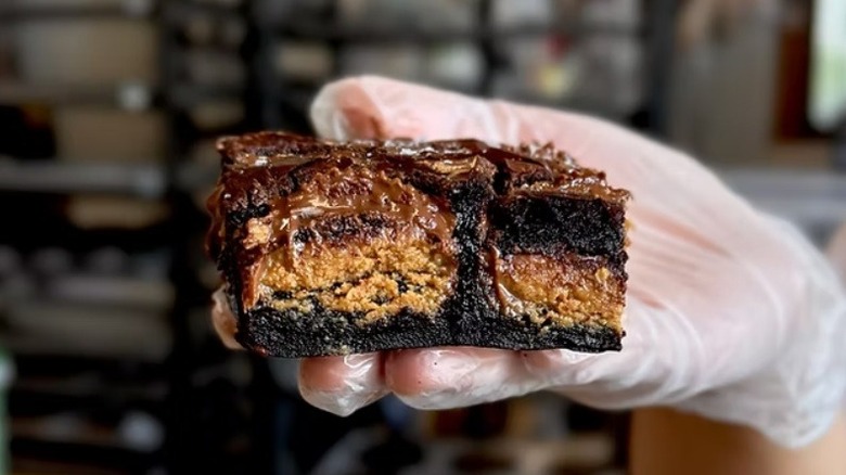 Gloved hand holding brownie filled with Reese's cups