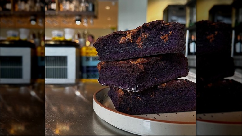 Three ube white chocolate brownies stacked on plate