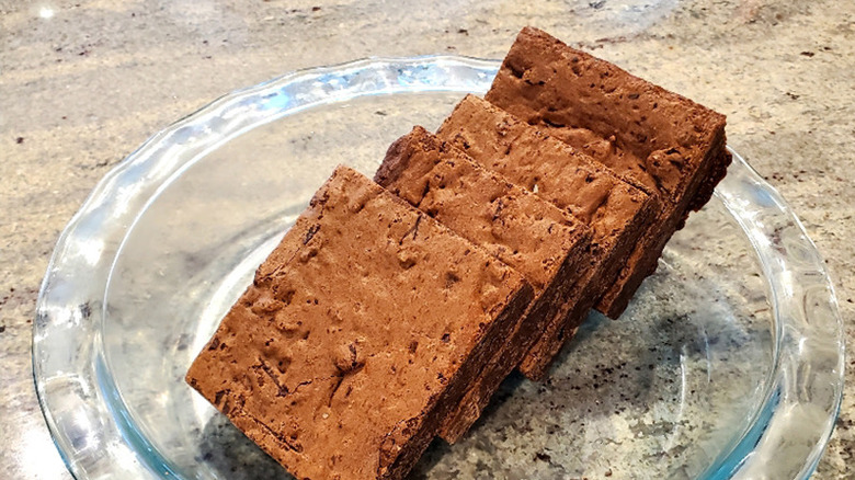 four brownie squares arranged on glass plate