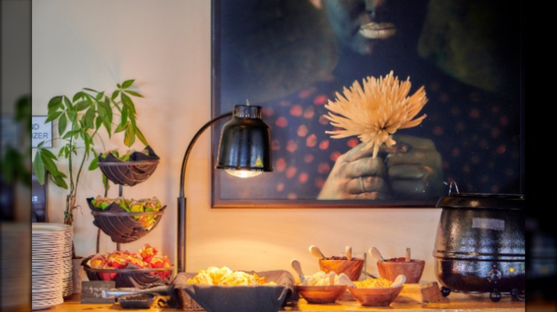 Buffet spread in front of artwork of person holding flower