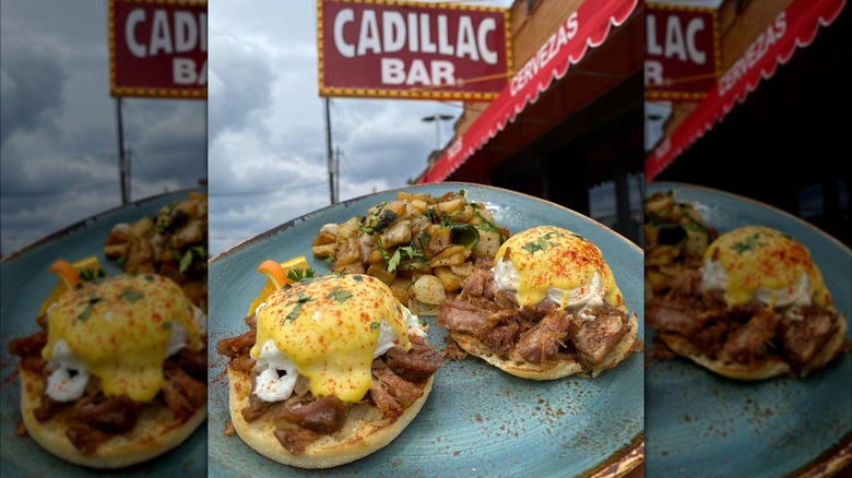 Eggs Benedict on plate outside in front of the sign for Cadillac Bar