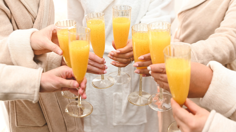 Group of people toasting with mimosas