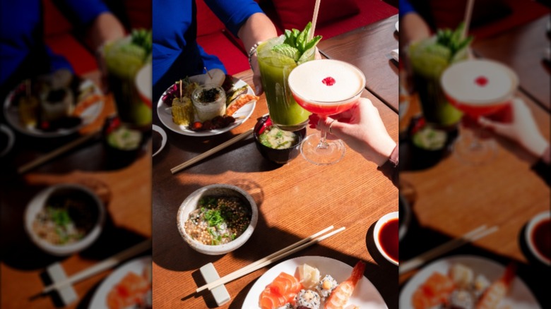 Toasting with cocktails over table with brunch seafood dishes