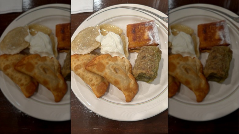 Pierogi with sour cream on a white plate on a wooden table