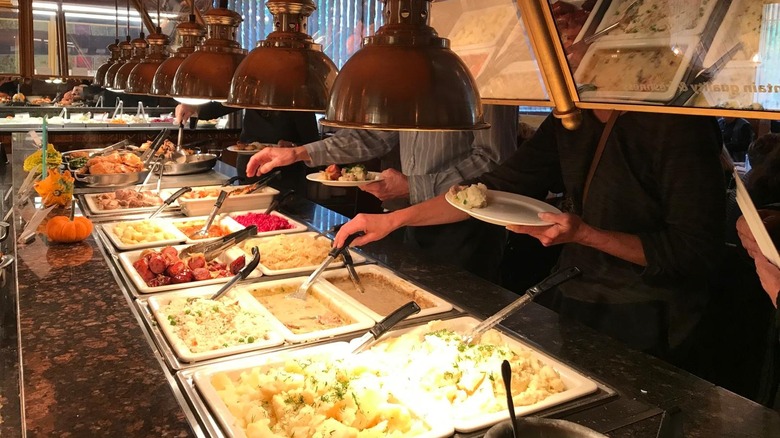 Hands reaching into a buffet of Polish food