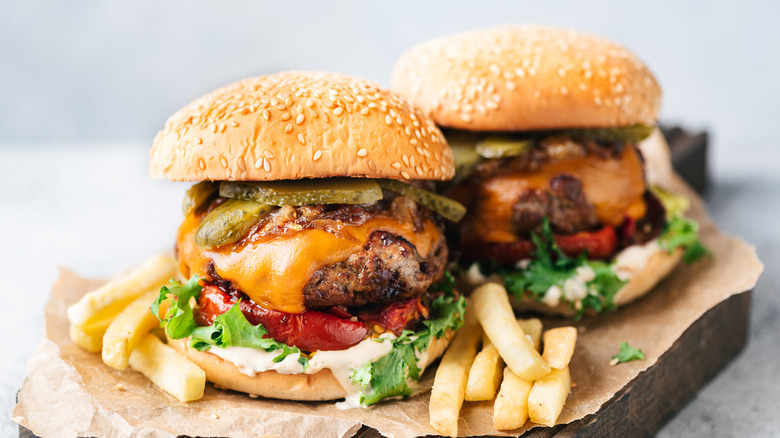 Two burgers with bacon on wood board