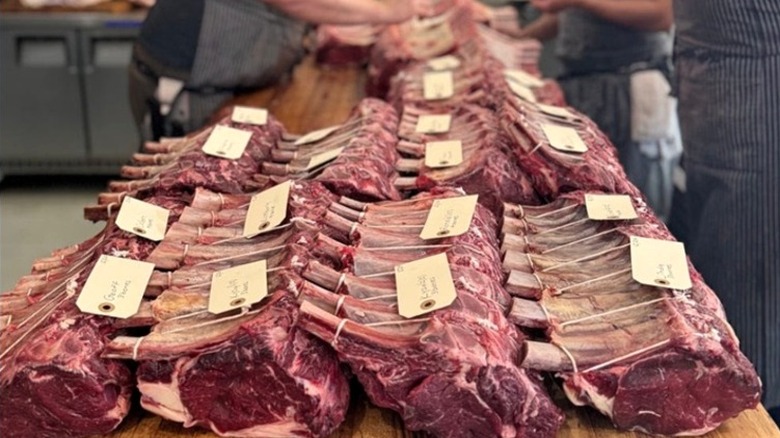 Rows of fresh cut bone-in ribeye steaks lined up on butcher block.