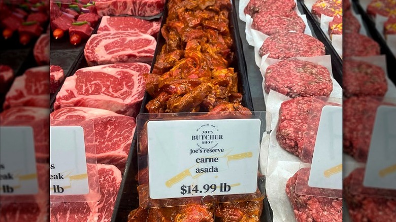 Butcher shop display case with fresh cuts of meat and prepared meats.