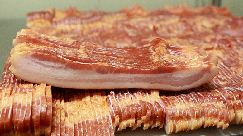 Piles of fresh sliced bacon.