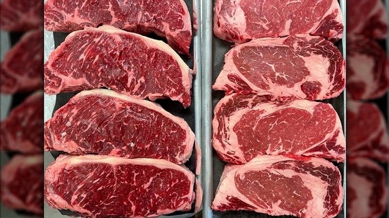 Two rows of sliced fresh cuts of well-marbled steaks.