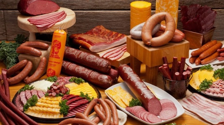 A display of various cured meats and cheeses on plates, platters, and platforms.