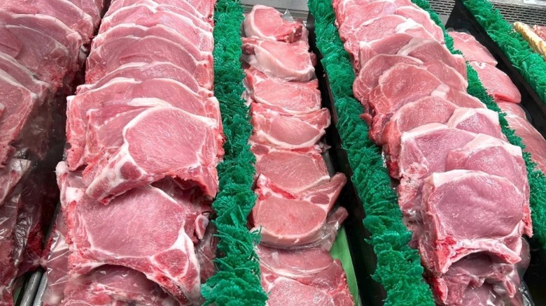 Rows of raw pork chops lining butcher case.