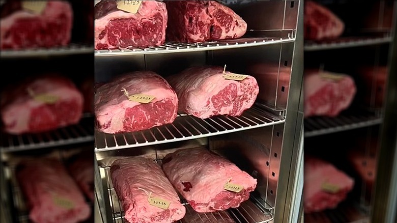 Standing refrigerator racks with large raw cuts of beef roasts