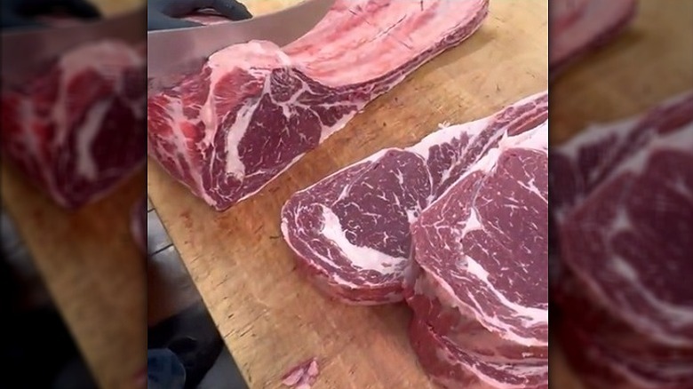 Rib roast being cut into individual tomahawk ribeyes.