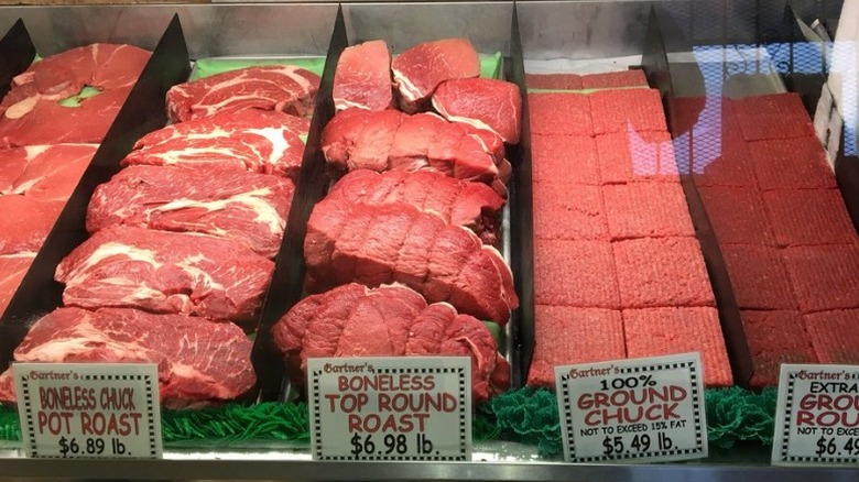 Rows of raw beef cuts in butcher display case.