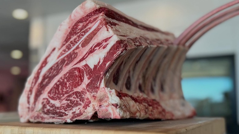 Large chunk of bone-in rib roast on cutting board.