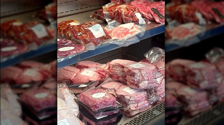 Shelves of packaged raw meat in butcher case.