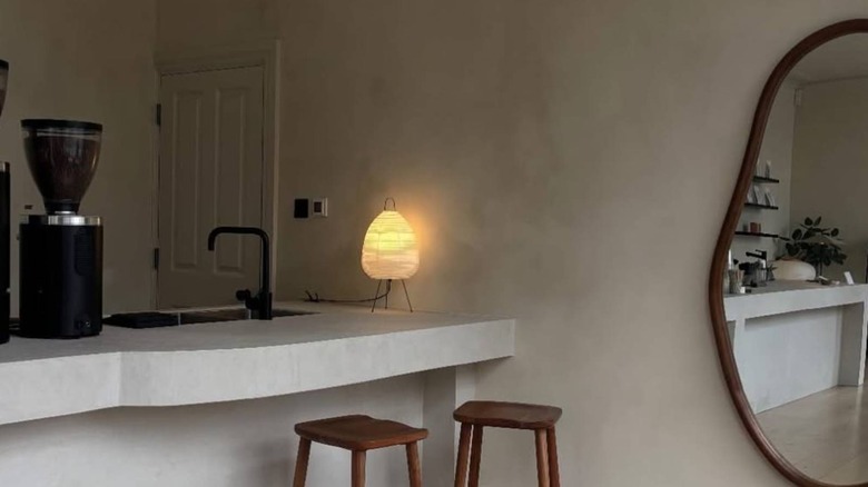 Minimalist interior of Lane Eight Coffee with gray walls, wooden stools and a wavy mirror