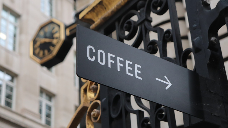 A black sign pointing to a coffee shop in central London